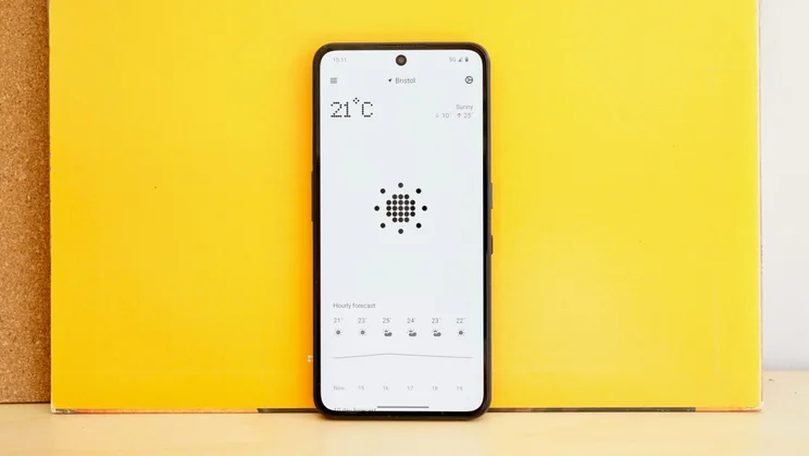 CMF Phone 2 Pro in front of a yellow backdrop, with the display showing the weather app