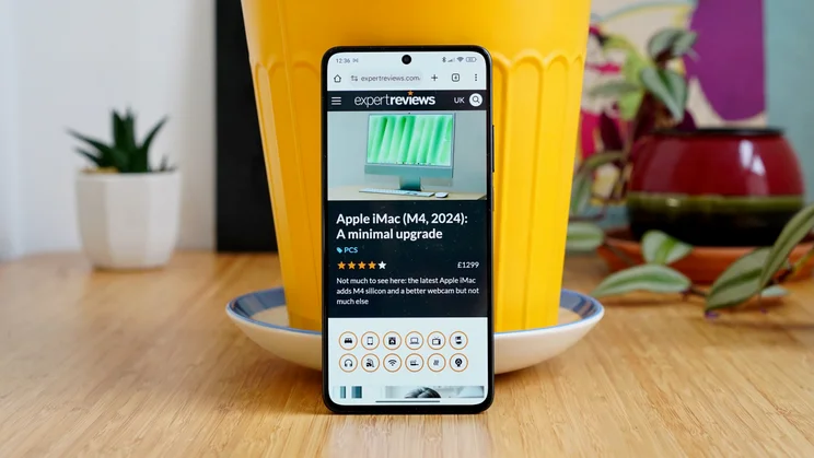 Xiaomi Poco X7 Pro leaning against a yellow pot, display showing the Expert Reviews homepage