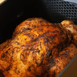 Air fryers are replacing UK takeaway - featured. Close up of a cooked chicken in an air fryer basket