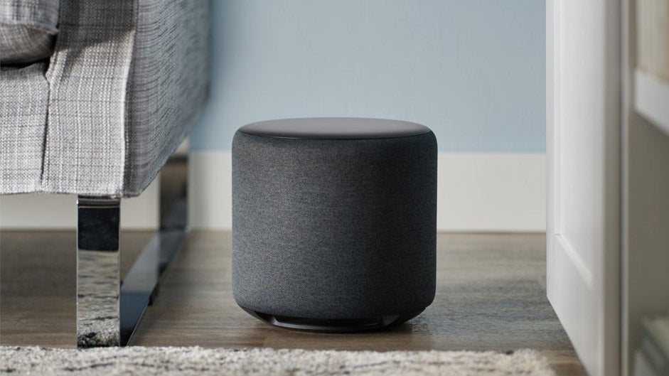 Amazon Echo Sub in black next to a sofa