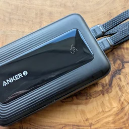 The Anker Zolo A1680 power bank pictured from above with two USB-C cables connected, on a walnut tabletop
