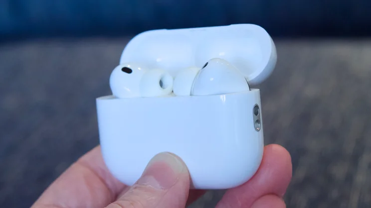 The. Apple AirPods Pro 3 in the charging case being held in the fingertips