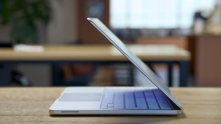 Apple MacBook Neo, half open, in silver, pictured right side