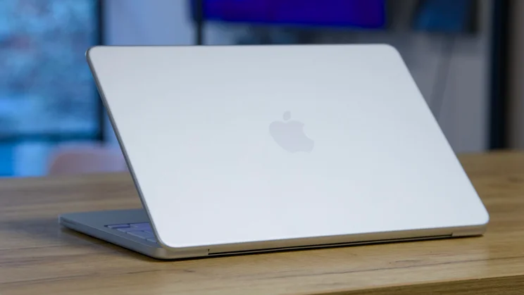 Apple MacBook Neo in silver, half open, pictured from the rear right quarter