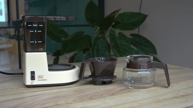 The Melitta Aromaboy on a table with the filter cone and jug next to it
