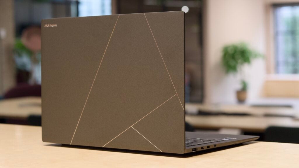 The rear of the Asus Zenbook S 14 UX5406S on a wood table in an office setting