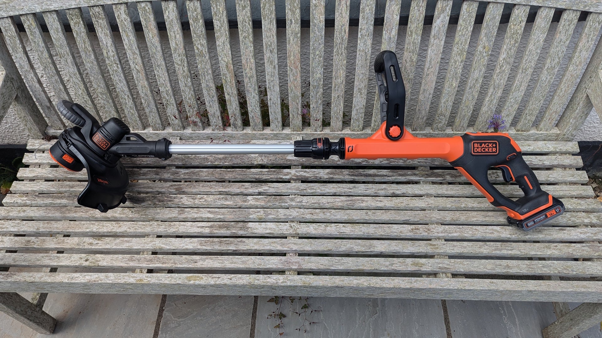 Black + Decker 18V PowerConnect Cordless Strimmer 28cm on a wooden bench