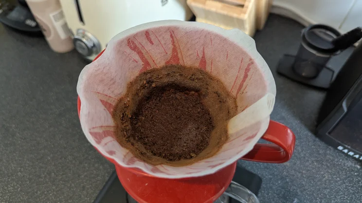 A bird's eye view of the leftover coffee grounds in a V60 filter cone after brewing