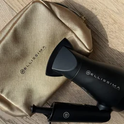 Bellissima Italia B-Travel gold travel bag with folded hair dryer resting on it