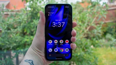 Google Pixel 9a in hand, in front of a window