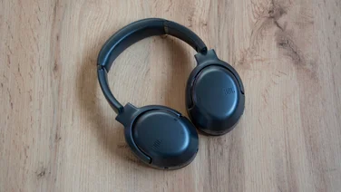 Aerial shot of the JBL Tour One M2 headphones on wooden floor background with their earcups facing the ground