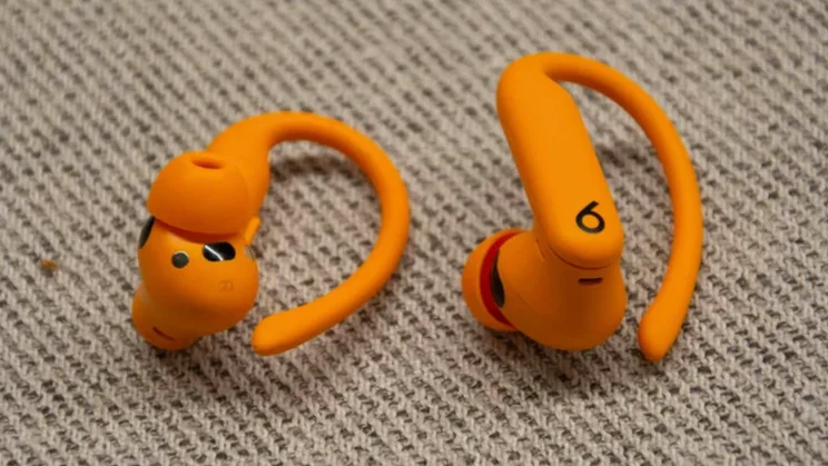 The Beats Powerbeats Pro 2 wireless earbuds on a textured surface