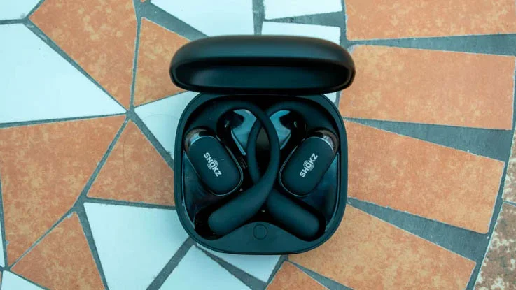 The Shokz OpenFit 2 Plus wireless earbuds on a ceramic table