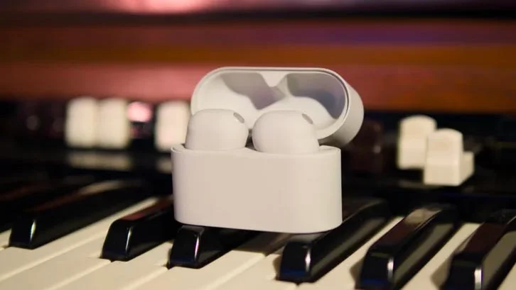 The Sony WF-1000XM6 true wireless earbuds in their case on a piano