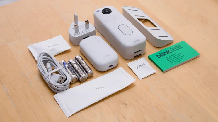 The Blink Video Doorbell 2nd generation and box contents arranged on a pale wood table, shot at an angle