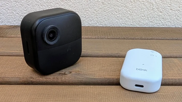 The Blink Outdoor 4 camera and its sync module on a wooden table