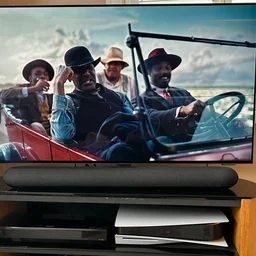 The Bluesound Pulse Cinema Mini soundbar on a TV stand in front of a Philips television