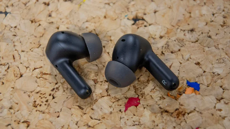 The Cambridge Audio Melomania A100 wireless earbuds on a cork table, with their eartips facing towards each other