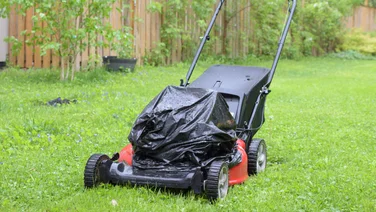 lawn power parked outside in rain, bin bag over motor