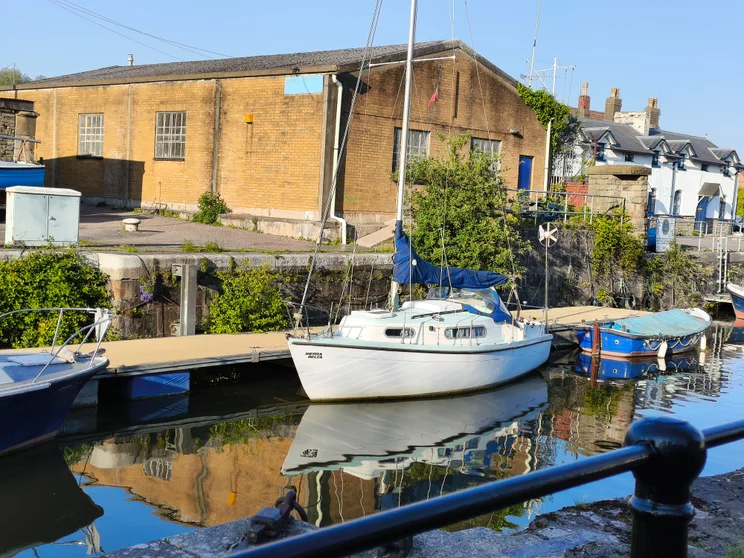 2x telephoto shot of a boat on a river, with buildings on the opposite shore