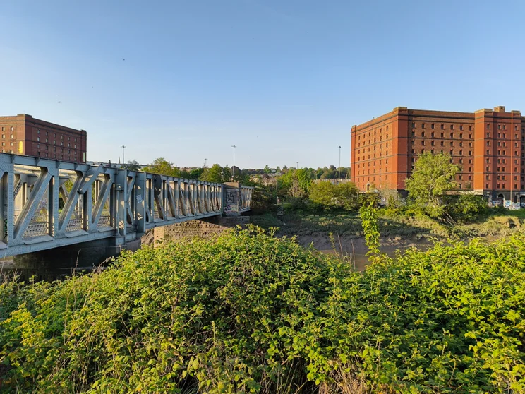 A bridge crossing a river, orange buildings on the opposite side