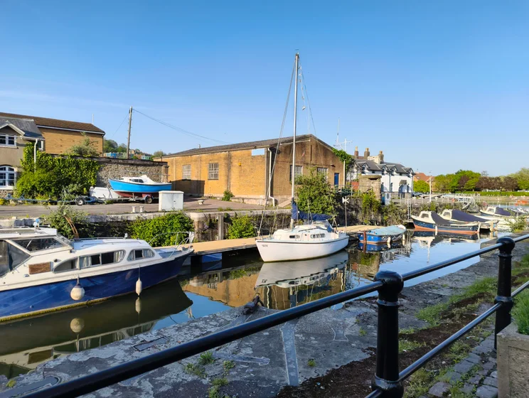 A boat moored on a river, buildings on the opposite shore