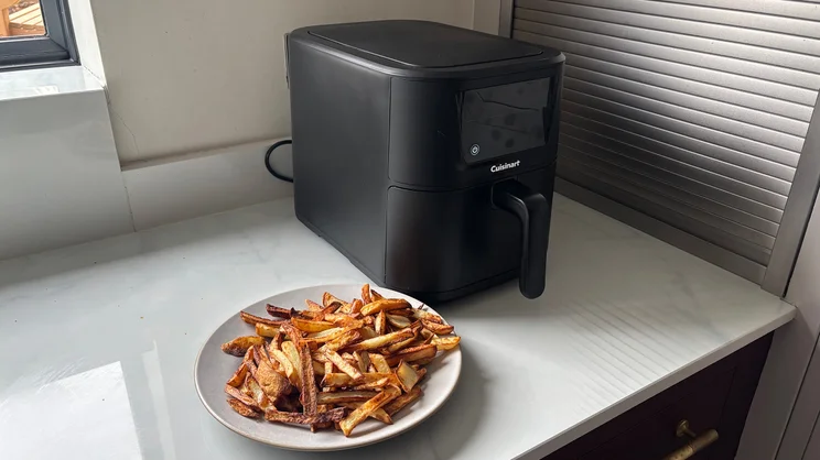 A plate of cooked chips in front of the Cuisinart Compact Max Air Fryer, on a ktichen worktop