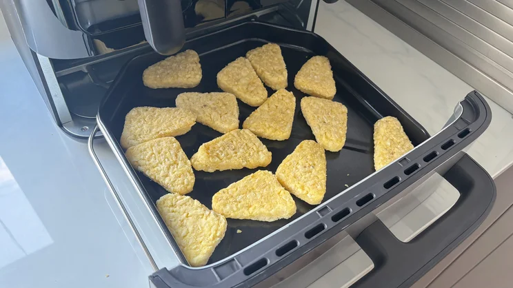 Uncooked hash browns on the flat bottom compartment of the Cuisinart Tri Zone 13.6l Air Fryer & Oven
