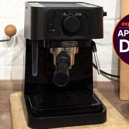 the De'Longhi Stilosa epsresso machine on a kitchen worktop. To the right of the machine, a badge reads "Expert Reviews Approved Deal"