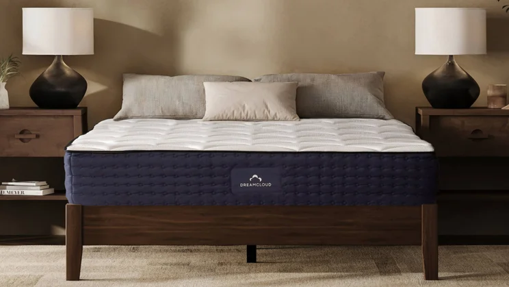 Dreamcloud Luxury Hybrid mattress on brown bed frame with lamps either side
