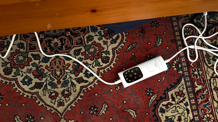 A bird's eye view of the Dreamland Love Mornings Heated Duvet remote and cable, on the floor