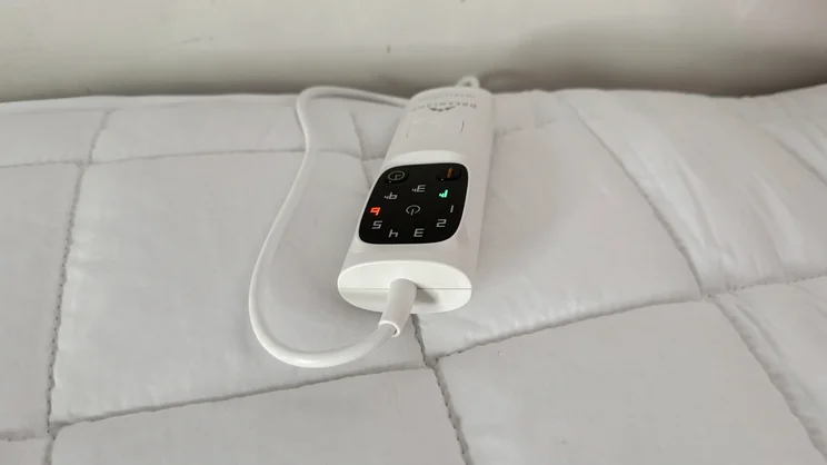 A closeup of the Dreamland Snowed In Heated Mattress Protector's remote cotrol