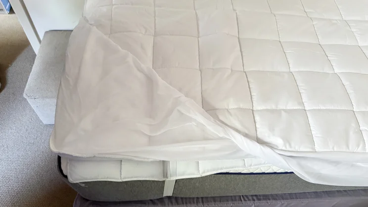 A bird's eye view of the Dreamland Snowed In Heated Mattress Protector, with one corner pulled back to show the fitted skirt