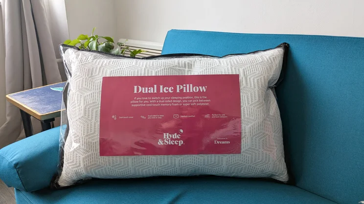 The Dreams Hyde and Sleep Dual Comfort Ice pillow in its storage bag, on a blue sofa in a living room