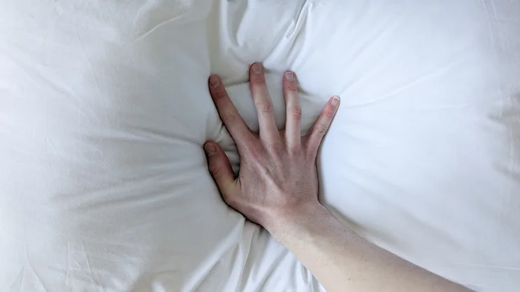 A bird's eye view of a hand pressing down on the surface of the Dreams Side Sleeper Pillow