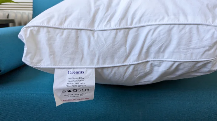 A closeup side view of the Dreams Side Sleeper Pillow, showing its care label