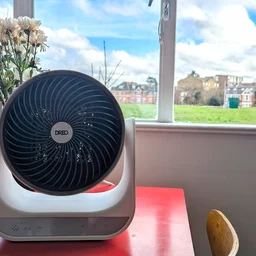 The Dreo Smart Whole Room Heater 714s on a red table, in front of a window