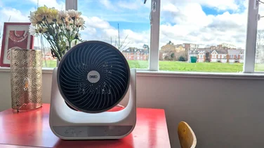 The Dreo Smart Whole Room Heater 714s on a red table, in front of a window
