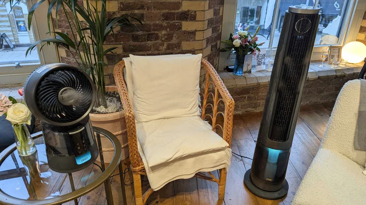 The Dreo TurboCool fans either side of a chair, in a showroom