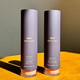 An image of the Dyson Chitosan pre-styling cream and post-styling serum on a wooden surface