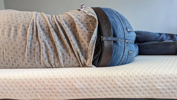 Firm, medium or soft. Person lying on a mattress on their side, view of their back and legs