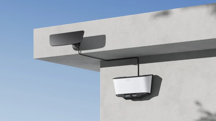 The Eufy Solar Wall Cam S4, mounted on a white rendered wall with its detachable solar panel mounted on the roof above it
