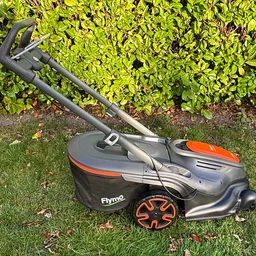 A side view of the Flymo 36V Ultramow 460 Duo, on a lawn in front of a hedge