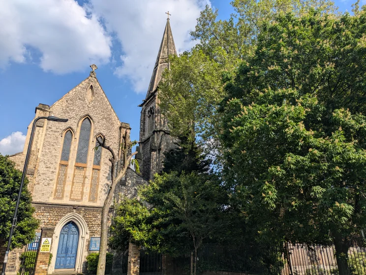 A church slightly obscured by a large tree