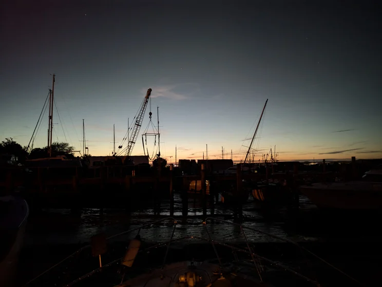 A silhouette of a dock at night with the setting sun just on the horizon