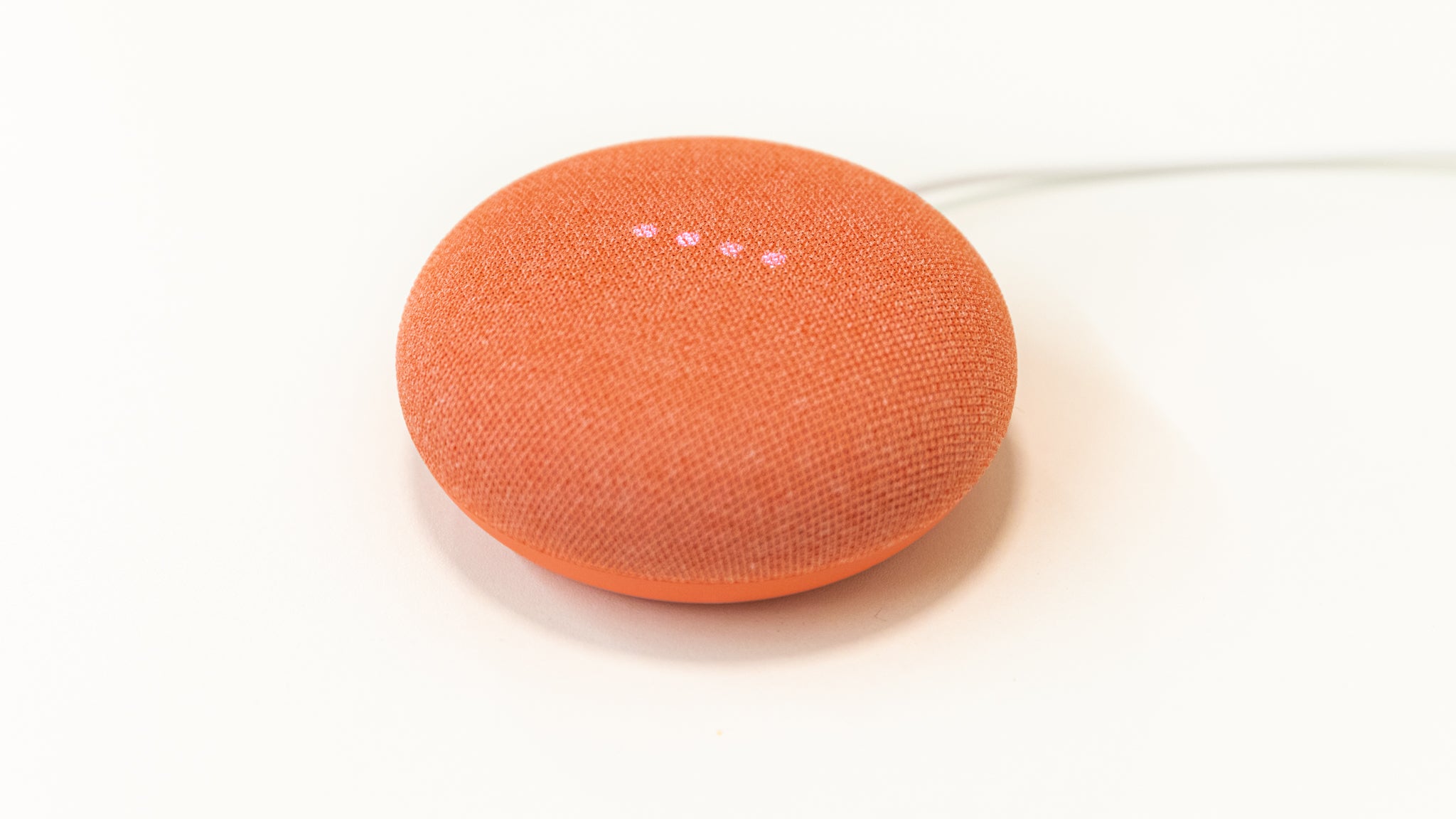 An orange Google Nest Mini (2nd gen) on a white surface