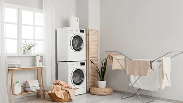 heated airer vs tumble dryer laundry room with washing machine, tumble dryer and airer with clothes on it