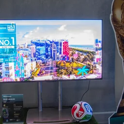 The 55in Hisense UR8S RGB Mini LED TV next to a cardboard cutout of the FIFA World Cup trophy