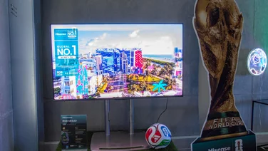 The 55in Hisense UR8S RGB Mini LED TV next to a cardboard cutout of the FIFA World Cup trophy