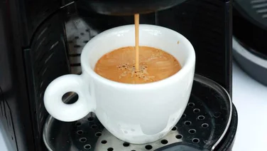 How much caffeine is in coffee - featured. Close up of coffee coming out of a coffee machine into a white cup